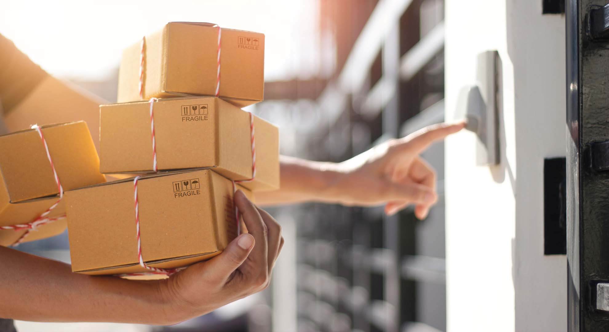 Man pressing a doorbell to deliver a pile of parcels