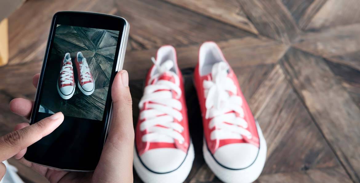 Person taking a photo of red shoes with a mobile phone