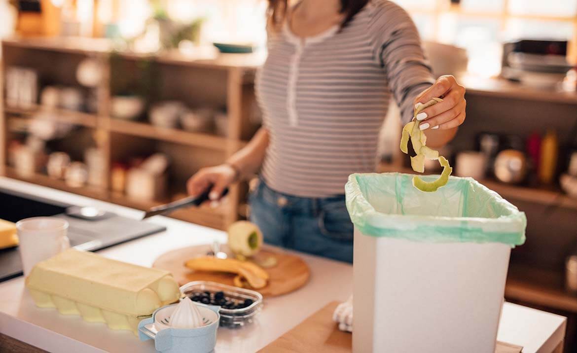 person putting food peelings into a food waste caddy.jpeg