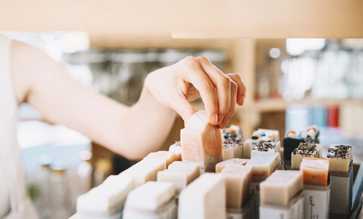 A persons hand picking up packaging free soap bars