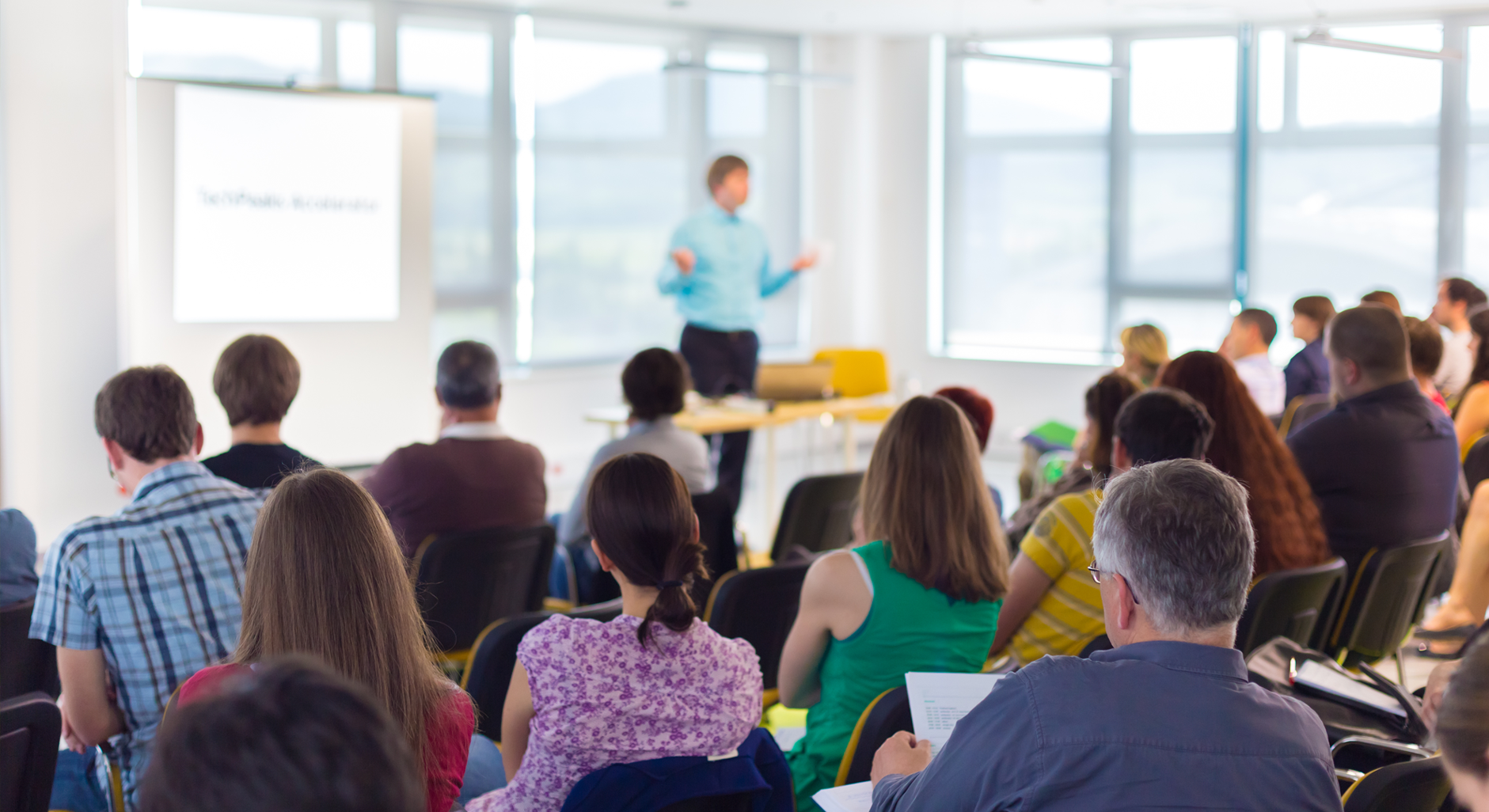 A room full of people listening to a speaker at a seminar