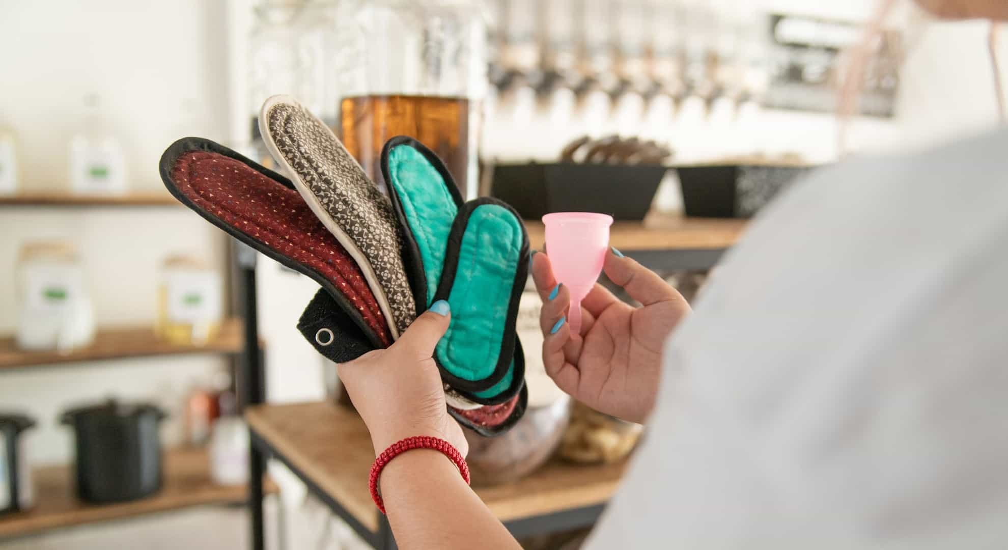 Woman comparing different reusable period products, pads and menstrual cups