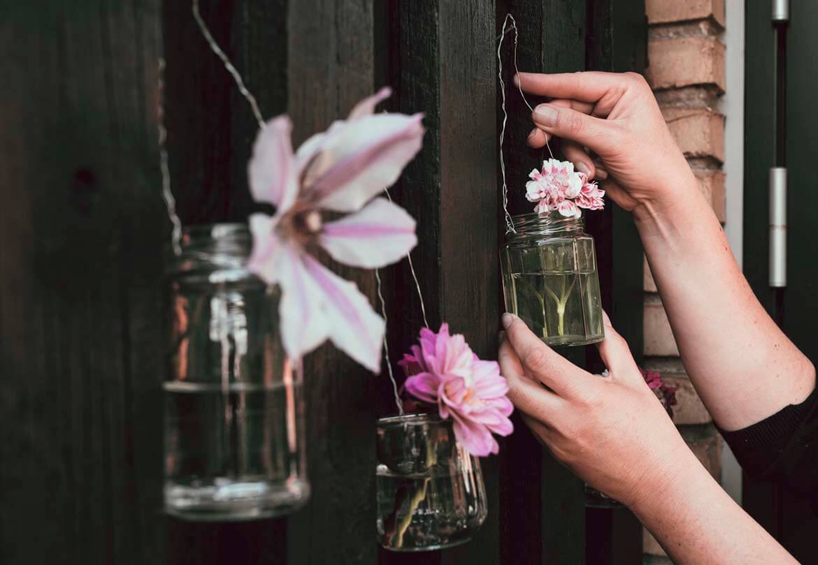 A person's hand hanging up upcycled jam jars as a decoration