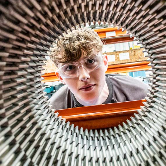  Name Photo of a person with curly hair looking wearing safety goggles and looking through a circular piece of machinery